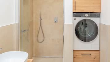 Ein Badezimmer mit Dusche, Waschmaschine und Holzschrank.