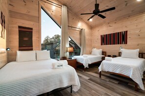 A wooden cabin-style bedroom with two beds, a ceiling fan, and a large window. - Smokiedoki Lodge - 3 Ensuite Bedrooms + Loft Near Parkway (Pigeon Forge)