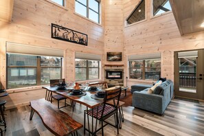 A spacious living area with a fireplace, wooden walls, and large windows. - Smokiedoki Lodge - 3 Ensuite Bedrooms + Loft Near Parkway (Pigeon Forge)