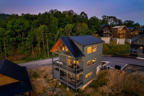 Ein mehrstöckiges Blockhaus mit Balkon, umgeben von Wald.