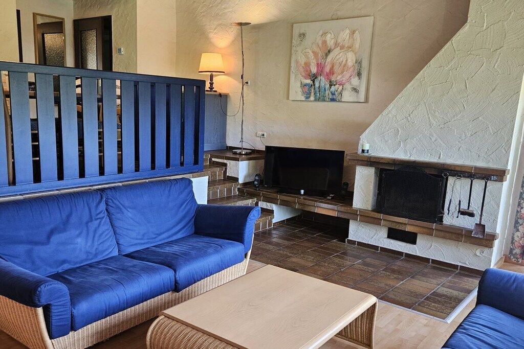 Un salon avec un canapé bleu, un téléviseur et une cheminée.