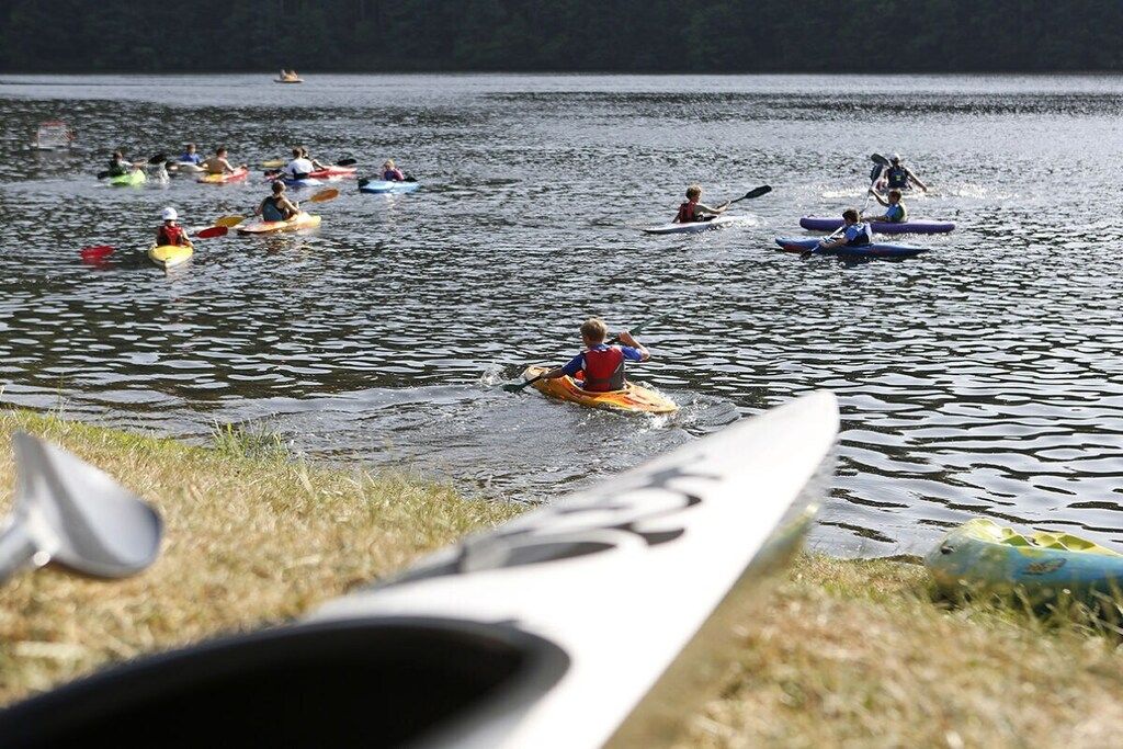 Un groupe de personnes pratiquant le kayak sur un lac calme.