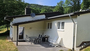 A single-story building with a covered patio area, a satellite dish, and a window.