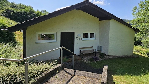 A small building with a door and windows, a bench, and a staircase leading up to the entrance.