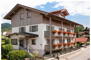 A multi-story building with balconies, a covered entrance, and a street view. - Holiday apartment with 1 bedroom (Bodenmais)