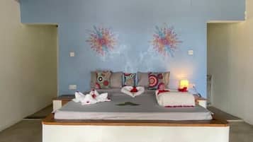 Een kamer met een bed, kussens, een nachtkastje en een wand met bloemwerk.