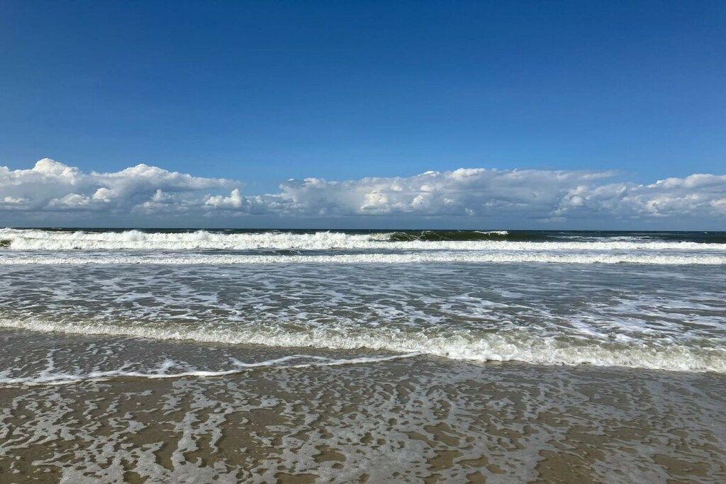 Een strand met golven die de kust naderen onder een heldere hemel.