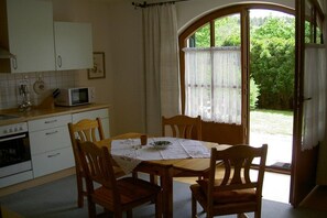 A kitchen with a dining table, chairs, a microwave, and an oven. - Holiday apartment with 1 bedroom (Passau - Salzweg)