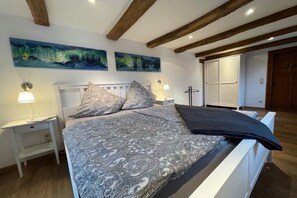 A bedroom with a bed, nightstands, a wardrobe, and two paintings on the wall. - Timber-framed holiday home 1764 (Eslohe)