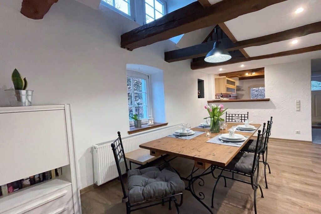 A dining area with a wooden table, black chairs, and a window with a view.