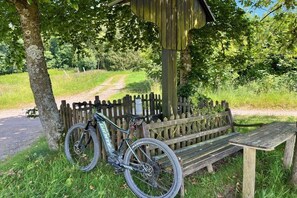 A wooden bench under a shelter, a bicycle, and a dirt path in a park. - Timber-framed holiday home 1764 (Eslohe)