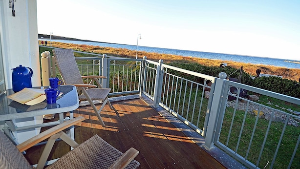 A balcony with a view of the beach, a table with chairs, and a railing. - Right on the Baltic Sea beach with a view of the sea!, 20 meters to the beach, washing machine, sleeps 2 (Glowe)