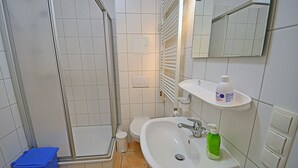 A bathroom with a shower, toilet, sink, and a mirror. - Right on the Baltic Sea beach with a view of the sea!, 20 meters to the beach, washing machine, sleeps 2 (Glowe)