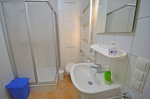 Un bagno con doccia, WC, lavandino e specchio.
