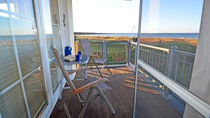 A balcony with a view of the beach, a table with chairs, and a blue container. - Right on the Baltic Sea beach with a view of the sea!, 20 meters to the beach, washing machine, sleeps 2 (Glowe)