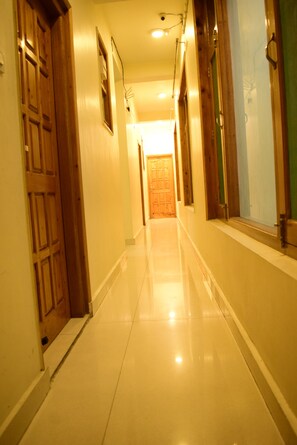 A corridor with wooden doors and a tiled floor leading to a room with a green wall.