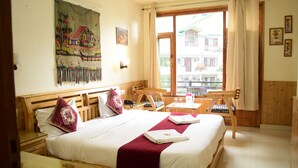 Habitació d'hotel amb un llit gran, un panell de capçalera de fusta, un quadre a la paret, una finestra amb cortines i vistes a edificis.