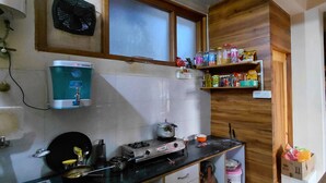 Una cuina amb dispensador d'aigua, fogó i prestatges amb diversos aliments.