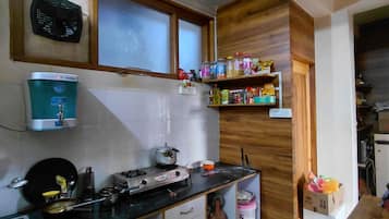 Una cocina con dispensador de agua, estufa y estantes con diversos alimentos.