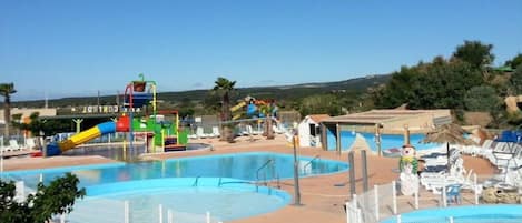 A pool area with multiple swimming pools, a water slide, and lounge chairs.
