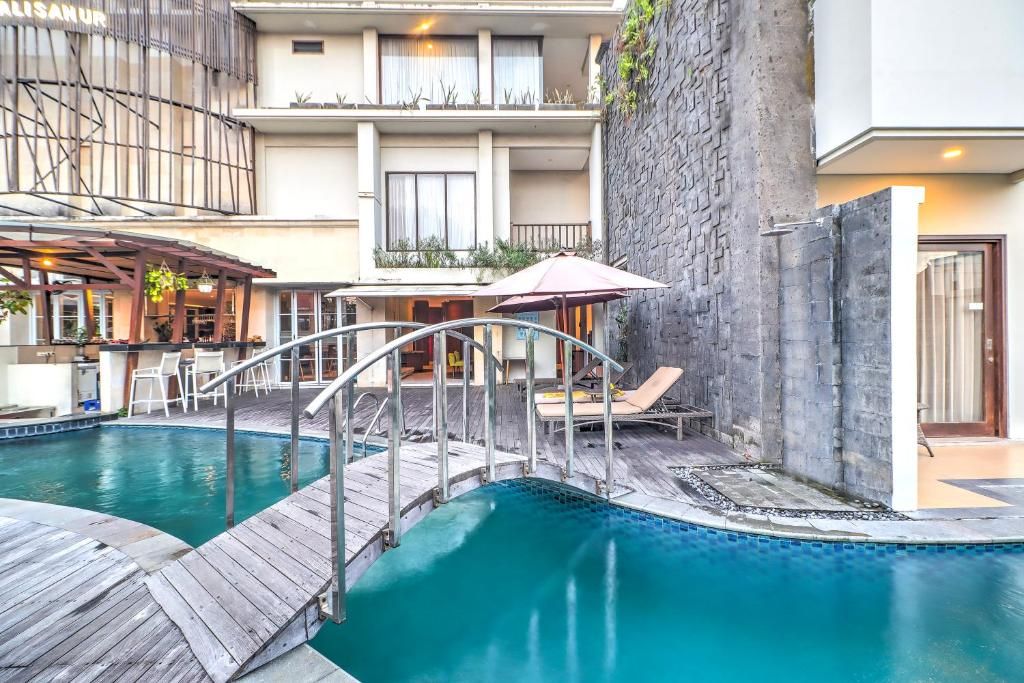 A swimming pool with a wooden deck, lounge chairs, and a stone wall.