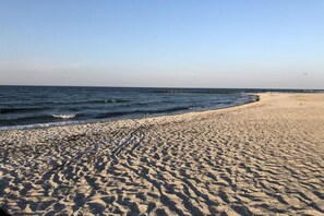 Ein Strand mit blauem Himmel, ruhiger See und sandigem Ufer.