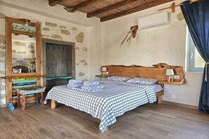 Ein rustikales Schlafzimmer mit einem hölzernen Bett, einem kleinen Tisch, einem Spiegel und einer Steinwand.