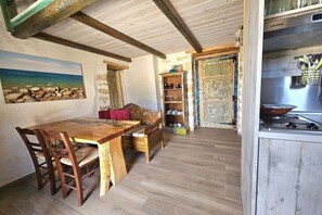 Ein rustikaler Essbereich mit Holztisch und -stühlen, einer Bank und einem Bild von einer Strandansicht.