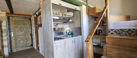 Cocina compacta con encimera de madera, un lavabo y una escalera que sube a un nivel superior.
