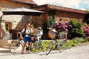 Ein Gebäude aus Stein mit einem Ziegeldach, einem Korbstuhl und einem Fahrrad.