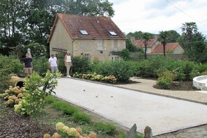 A courtyard with a paved path, a stone building, and lush greenery. - Chateau le Colombier "Le Poirier" (Brévands)