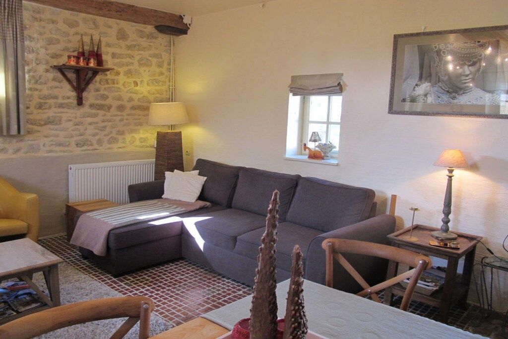 Ein gemütliches Wohnzimmer mit einer Couch, einem kleinen Tisch, einer Lampe und einer Steinwand.