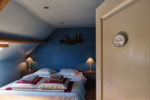A bedroom with a bed, two bedside lamps, a shelf with decorative items, and a wall-mounted light switch. - Chateau le Colombier "Le Poirier" (Brévands)