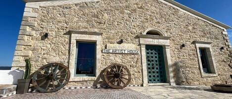 Un edificio de piedra con un letrero que dice 'The Artist House' y dos grandes ruedas de madera en la parte delantera.