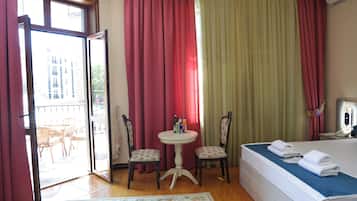 Ein Hotelzimmer mit einem Bett, zwei Stühlen, einem kleinen Tisch und einem Fenster mit Vorhängen.