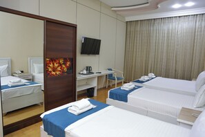 Habitación de hotel con dos camas, un escritorio, una silla, un televisor y un baño.