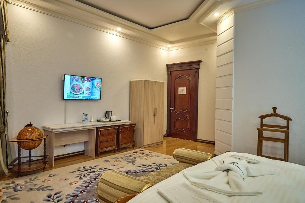 A hotel room with a bed, a desk, a television, a wardrobe, and a globe on a stand.