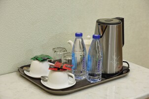 Una bandeja con cafetera, dos tazas, dos botellas de agua y una bolsita de té.