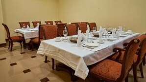 A dining room with a long table set for a meal, surrounded by upholstered chairs. - Queens Hotel (Tashkent)
