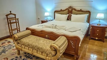A bedroom with a large bed, bedside tables, a bench, and a floral-patterned rug.