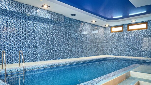 A swimming pool with a tiled wall and steps leading into it. - Queens Hotel (Tashkent)