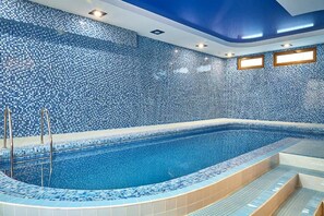 Une piscine avec un mur carrelé et des marches menant à l’intérieur.