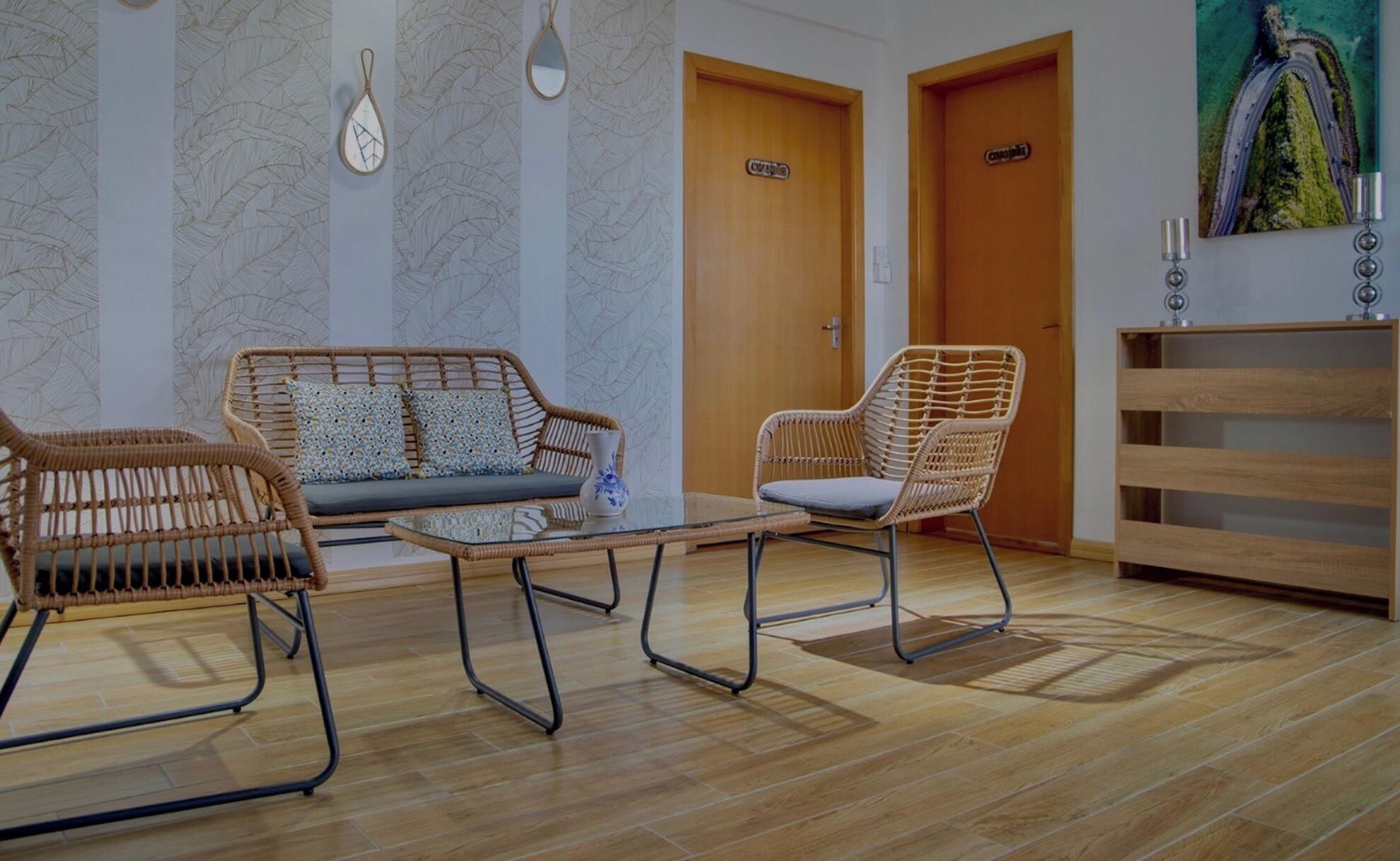 Une pièce comprenant un canapé, un fauteuil, une petite table et un meuble en bois.