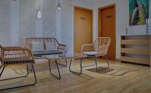A room with a sofa, a chair, a small table, and a wooden cabinet.