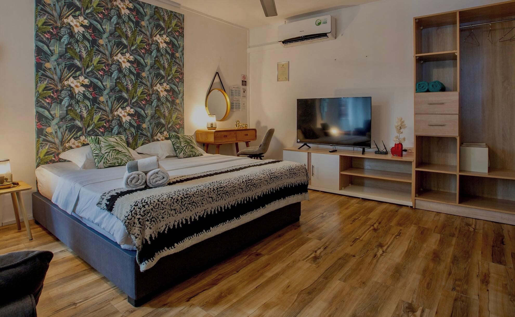 A modern bedroom with a bed, a TV, a desk, and a wardrobe.