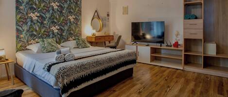 A modern bedroom with a bed, a TV, a desk, and a wardrobe.