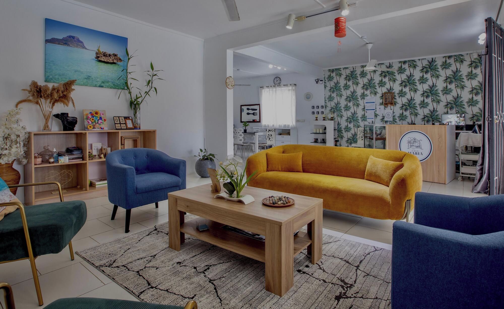 Un salon avec un canapé, des fauteuils, une table basse et un tableau au mur.