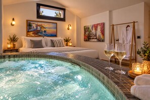 Ein Hotelzimmer mit einem Bett, einer Badewanne und zwei Gläsern Weißwein auf einem Tisch.