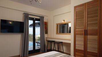 Ein Schlafzimmer mit einem Bett, einem Fernseher, einem Fenster mit Vorhängen, einem Holzschrank und einem kleinen Hocker.