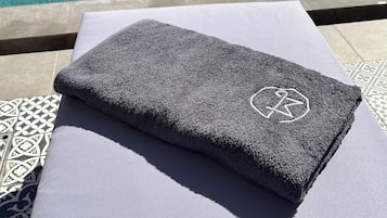 Ein Handtuch mit einem Logo auf einer weißen Fläche in der Nähe eines Schwimmbeckens.